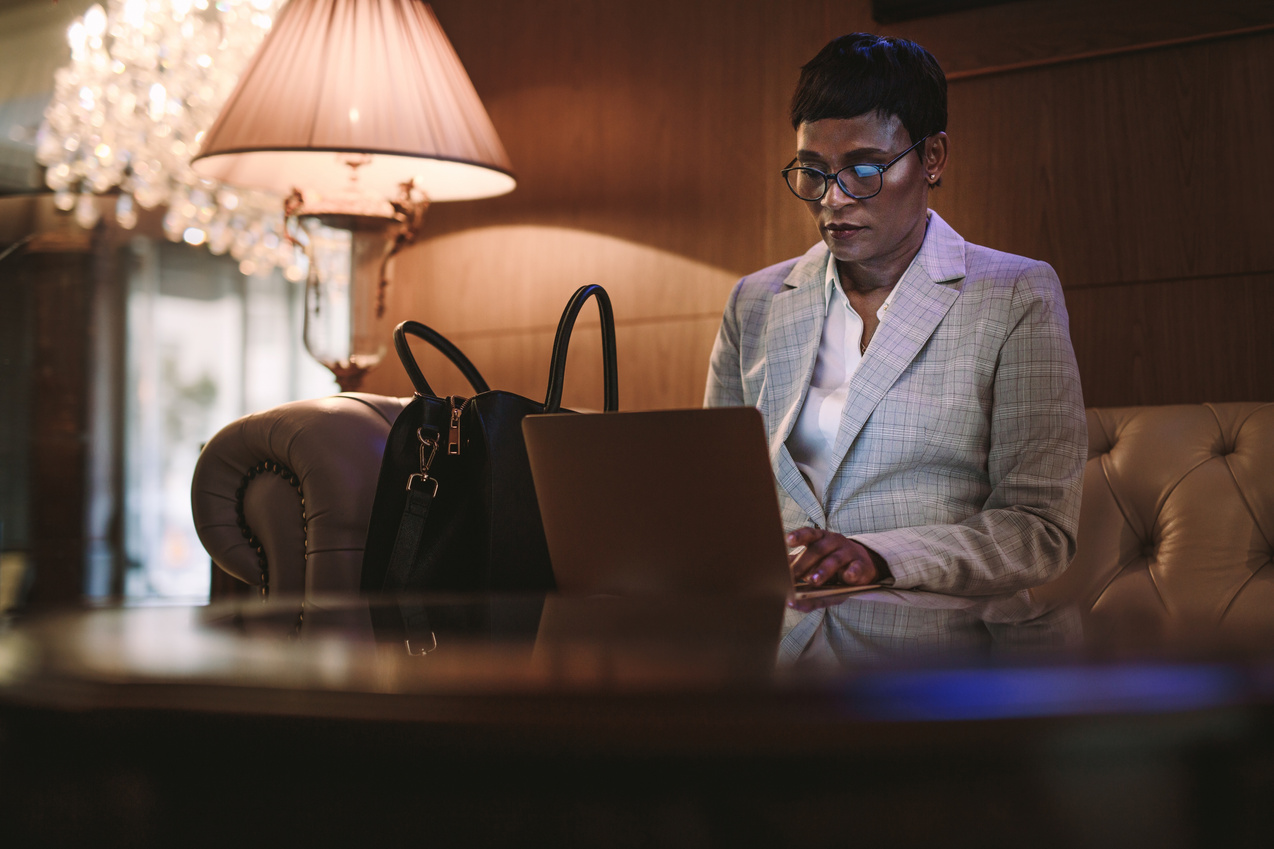 Female CEO on Business Trip Using Laptop in Hotel Lobby